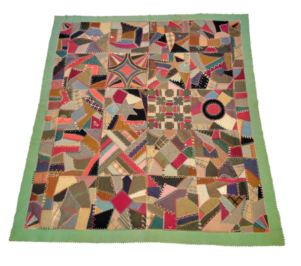 CRAZY QUILT: American, 1909, cotton, felt, silk. A pieced and tied crazy quilt with twenty distinct blocks, two narrow borders on two sides, and a bright green felt border, in a variety of fabrics with handstitche
