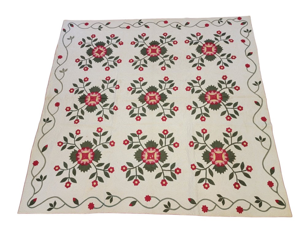 ROSE OF SHARON APPLIQUE QUILT: American, 19th century, cotton. A handstitched applique quilt with nine Rose of Sharon variant blocks with a vining floral and bud border in solid green and red with printed pink and yellow fabrics, a