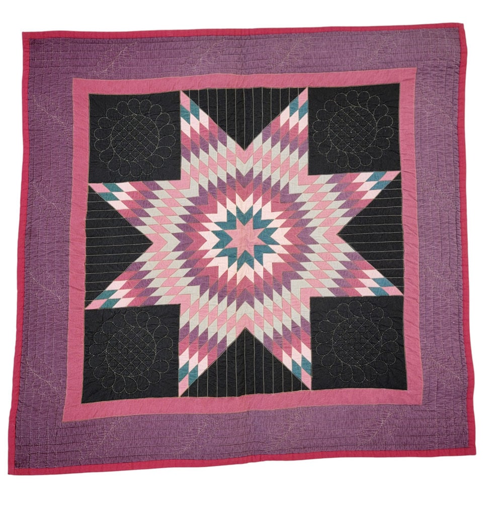STARBURST SAMPLER QUILT: American, cotton. A sampler size quilt with a large pieced starburst design in pink, purple, and turquoise fabrics with black quilted blocks. 49" by 39". Provenance: The Virginia Gunn Collection, Woos