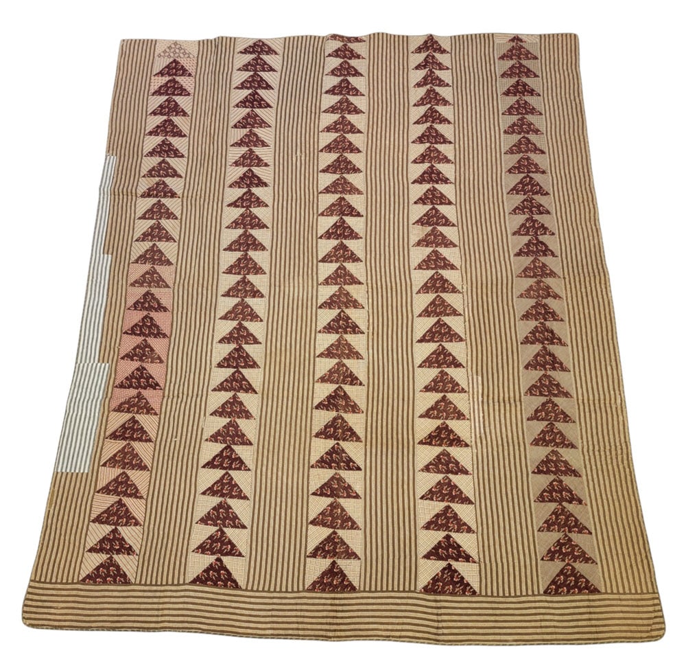 PIECED "FLYING GEESE" QUILT: American, 19th century, cotton. A pieced and handstitched quilt in burgundy and brown with alternating rows of a flying geese pattern and striped fabric. 87.5" by 74.5". Provenance: The Virginia Gunn