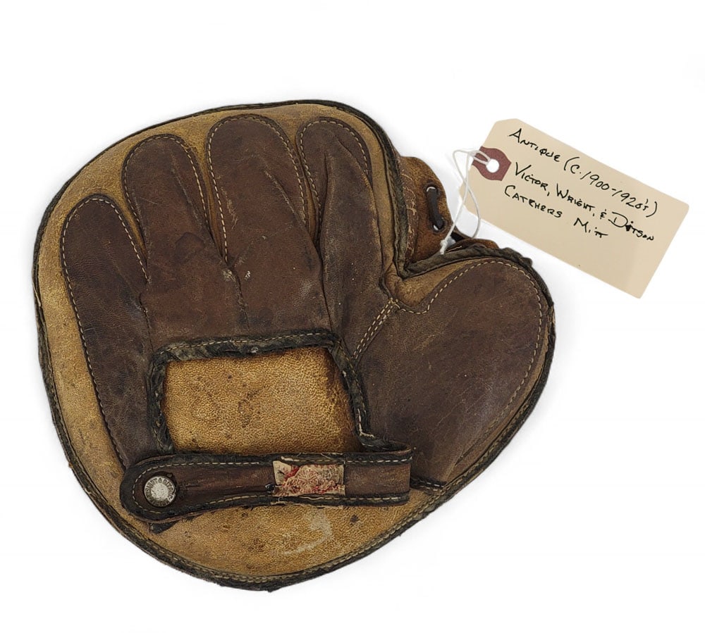 EARLY CATCHER'S MITT: Wright & Ditson-Victor, c. 1910. Heavily padded mitt with glove stitched to the back side. Worn label and legible button. 9" long , 9" wide. In 1910, the Wright & Ditson Company merged with the Victor