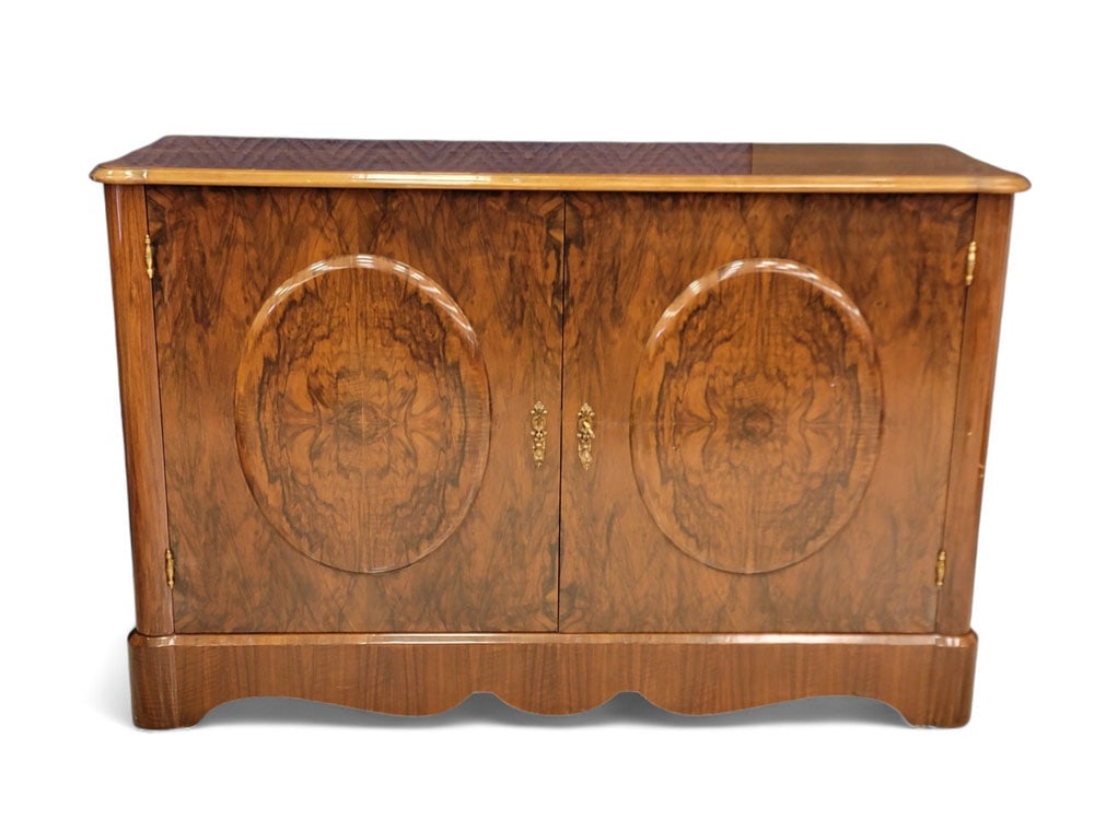 TROUVAILLES MAHOGANY CREDENZA: 20th century. Neoclassical-inspired design with highly polished flame mahogany veneers. Doors decorated with raised oval panels, brass hardware (with key). 36" high, 55" wide, 10" deep. From a Columbu