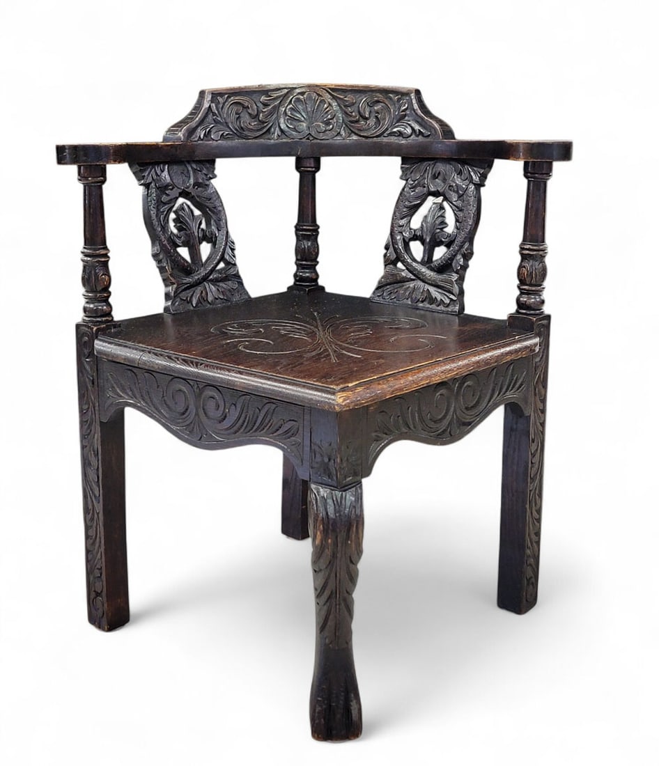 CARVED CORNER CHAIR: American, late 19th century. Chippendale-inspired form with round back, carved fish splats, fleur-de-lis design on seat, top rail with shell and acanthus leaves, foliate carvings on arms and legs. Ver