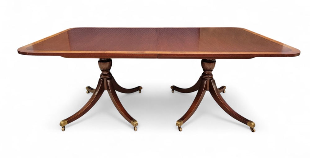 KITTINGER NEOCLASSICALDINING TABLE: Buffalo, New York, 20th century, Label on underside, patent no. 01601, serial no. 34. Double pedestal, each with four sabre-curved legs and brass-capped feet on casters. Mahogany-look finish with ligh