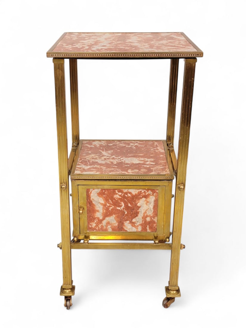 FRENCH ROUGE MARBLE AND BRASS NIGHTSTAND: France, c. 1900. Square profile with marble surfaces and sides, brass trim and legs on casters. Two shelves over a small compartment with door. Underside of top has Brevet? SGDG tag. 32" high, 15.5" w