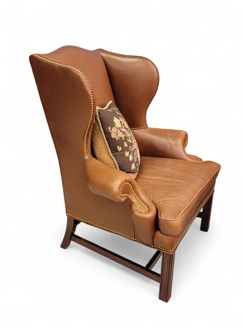 CHIPPENDALE-STYLE LEATHER EASY CHAIR & OTTOMAN: 20th-21st century. With camel back, scrolled arm rests, and straight legs. Brass nailhead trim. 21st century. Chair 46.5" high; ottoman 19" high, 27.5" wide, 19" deep. From a Columbus, Ohio collection