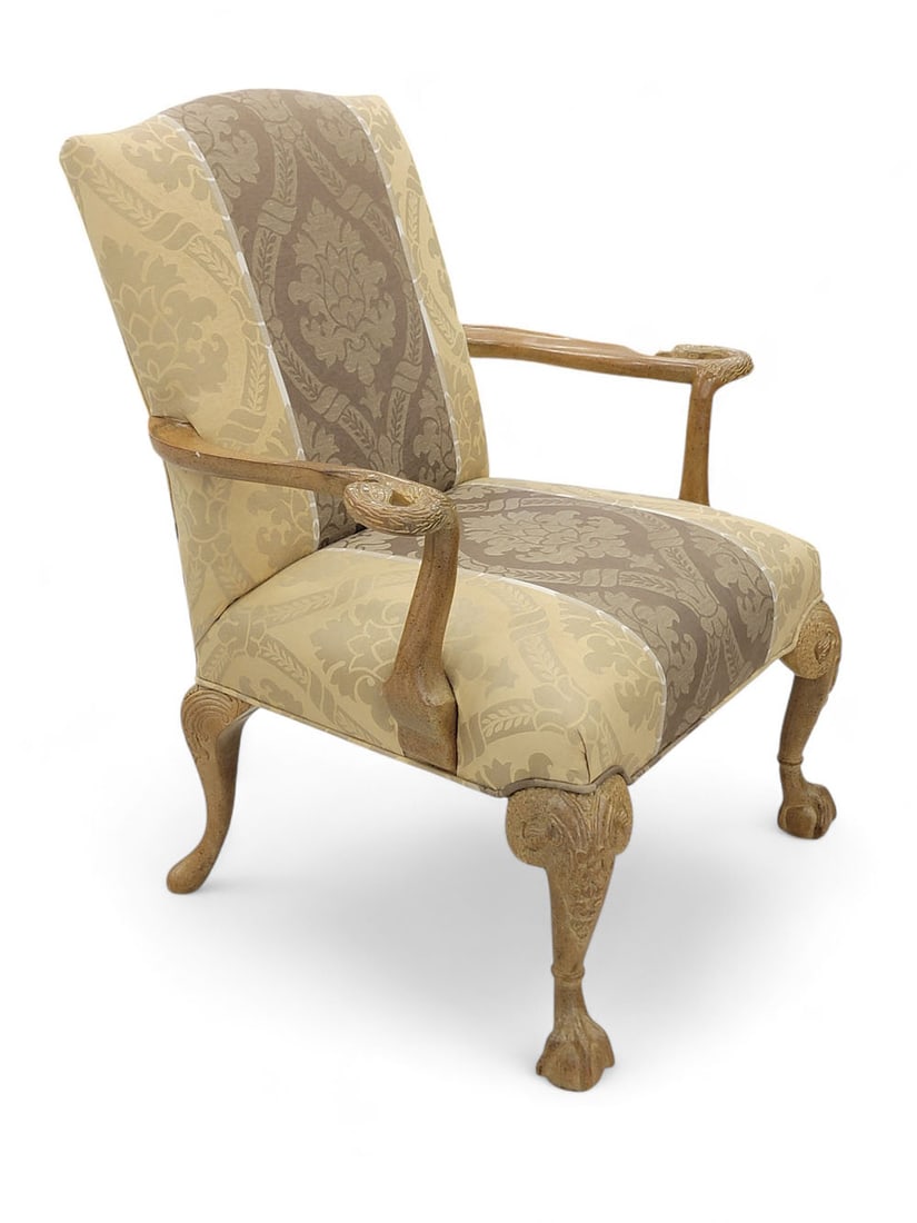 CHIPPENDALE-STYLE UPHOLSTERED ARM CHAIR WITH SWAN CARVINGS: 20h century. Arms terminate in swans' heads, repeated in tops of cabriole legs. Slight camelback, and ball-and-talon feet. Upholstered in gold and brown striped damask. Wood finished with golden hue.
