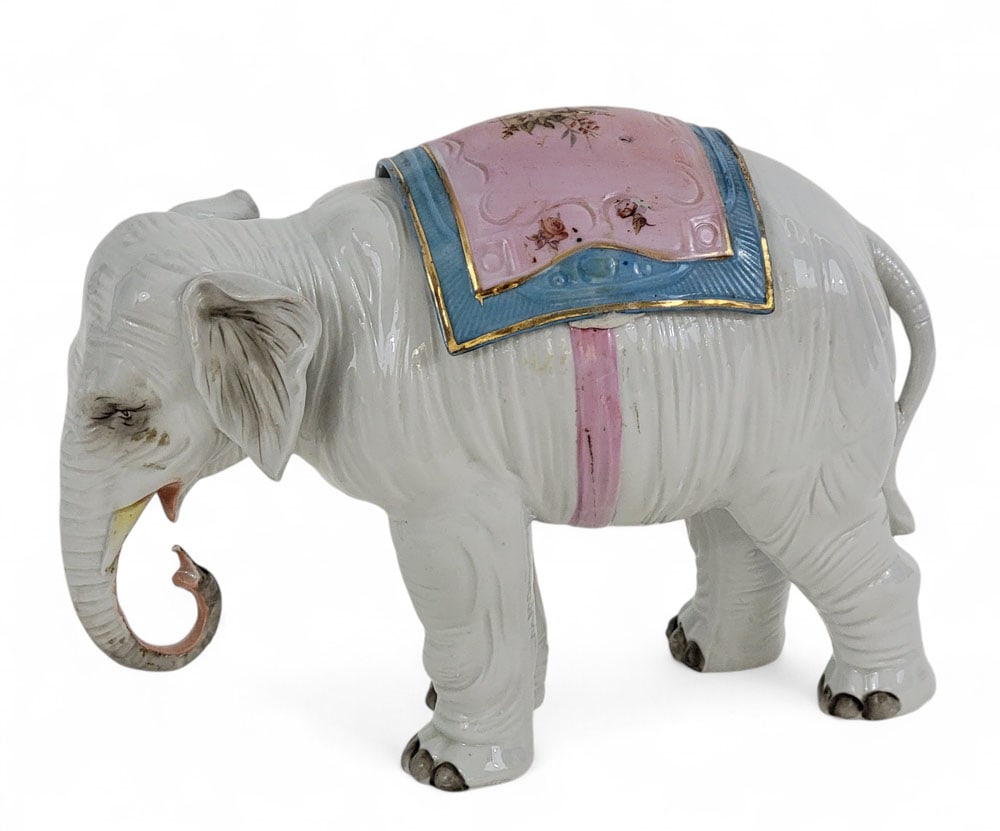 PORCELAIN ELEPHANT BOX: French, late 19th century. The saddle blankets lift off to reveal a box. 7" high, 9" long. Provenance: an Ohio collection. Affordable, in-house shipping is available for this lot. Please contact us fo