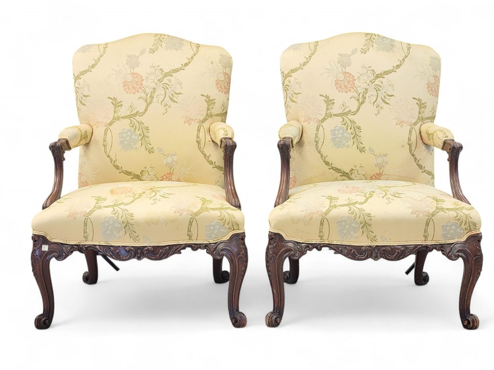 PAIR OF CHIPPENDALE-STYLE ARM CHAIRS: Late 19th-early 20th century. Highly carved serpentine front apron, with carved and scrolled legs and arm supports. Yellow flowered brocade upholstery with camel back. Bearing old Garth's auction tags