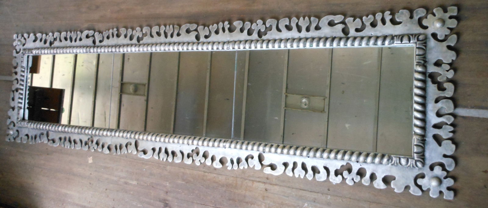 MONUMENTAL MIRROR BY DON DRUMM (OHIO, B. 1935): Akron, Ohio, 1990s, cast aluminum and glass. A bold frame, almost organic in appearance. Approx. 3' by 12'. Drumm made this mirror in the 1990s for the Armadillo Bar in Akron. The mirror remained in t