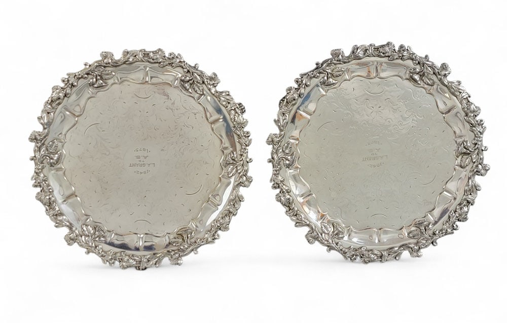 PAIR OF SHEFFIELD PLATE SALVERS: Unmarked, probably English, c. 1873. With elaborate foliate and floral rims, scroolwork engraving, and scrolled feet. Each with presentation inscription "1842 L.A. GRANT TO A.S. 1873." 12" diameter. P