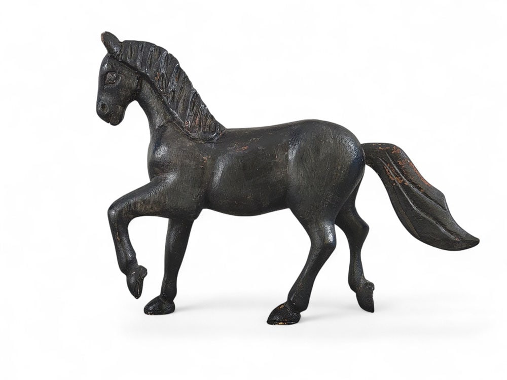 CARVED WOODEN HORSE: American, late 19th or early 20th century, wood. Carved striding horse with original black paint. An inverted triangle is inscribed into its right flank. Traces of white paint on its forelock. 9" high