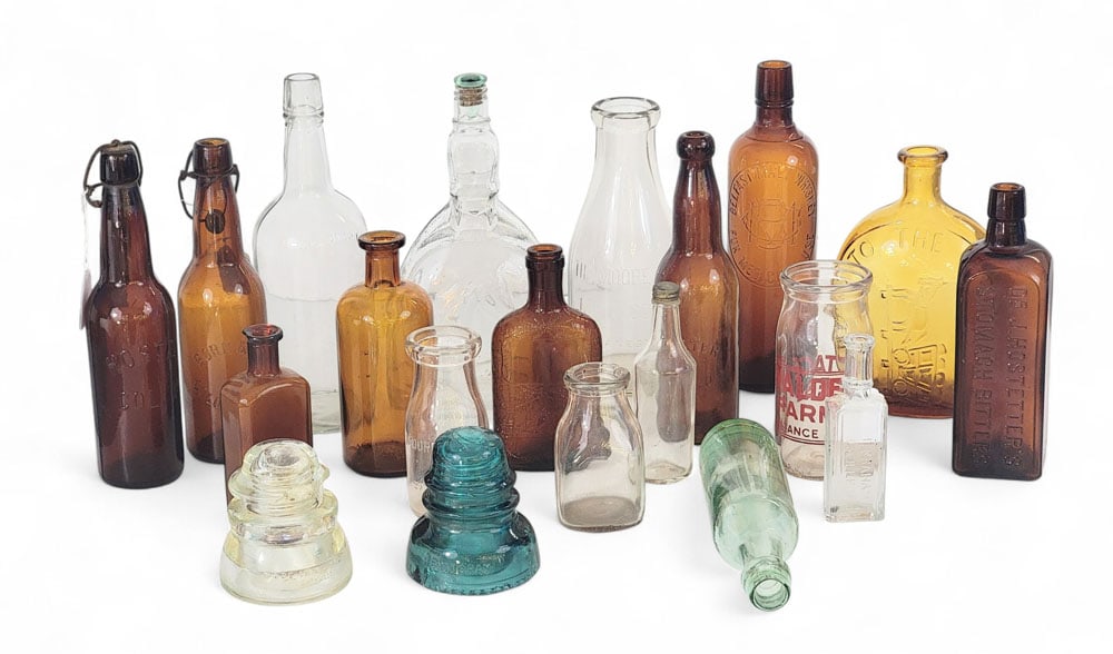 COLLECTION OF BOTTLES, FLASKS, ETC.: American, 19th-20th century. Includes eight amber bottles (Belfast Malt Whiskey, Dr. J. Hostetter's Stomach Bitters, and others); together with eight colorless bottles (including three Ohio milk bottl