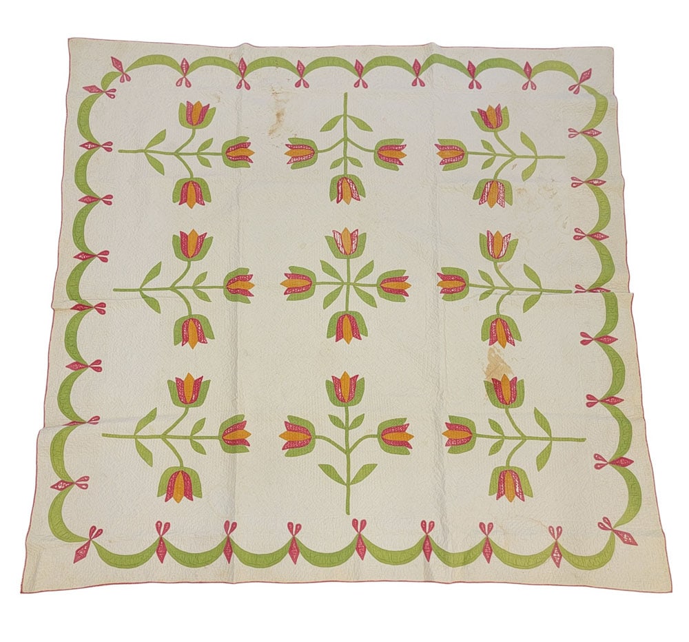 APPLIQUE TULIP QUILT: American, 19th century, cotton. An applique tulip quilt with flowers and stems revolving around central crossed tulips. Ribbon/swag border. Composed of solid green, pink, and cheddar fabrics on solid