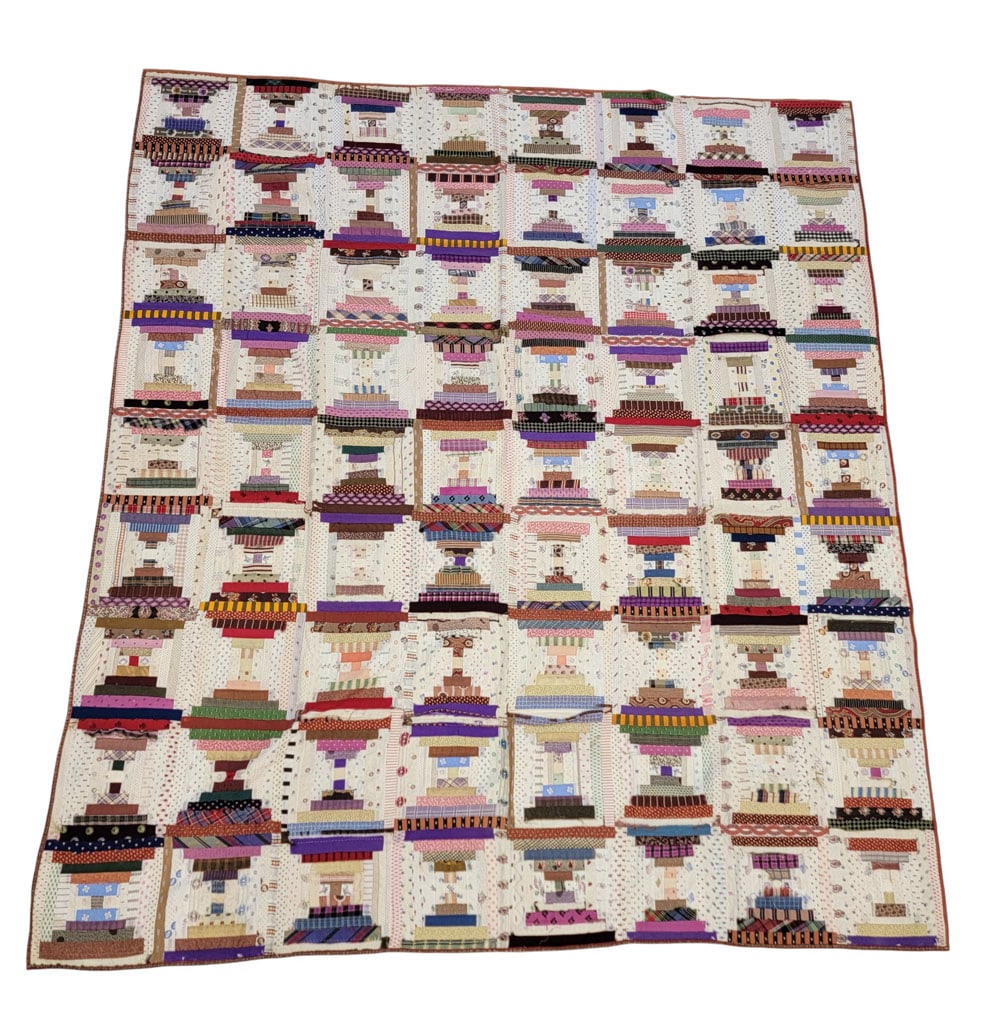 LOG CABIN SUMMER QUILT: American, early 20th century, mixed fabrics. A log cabin summer quilt composed of multicolor printed fabrics with emphasis on brown, red, purple, and white. Hand-stitched and quilted, no batting. 76"
