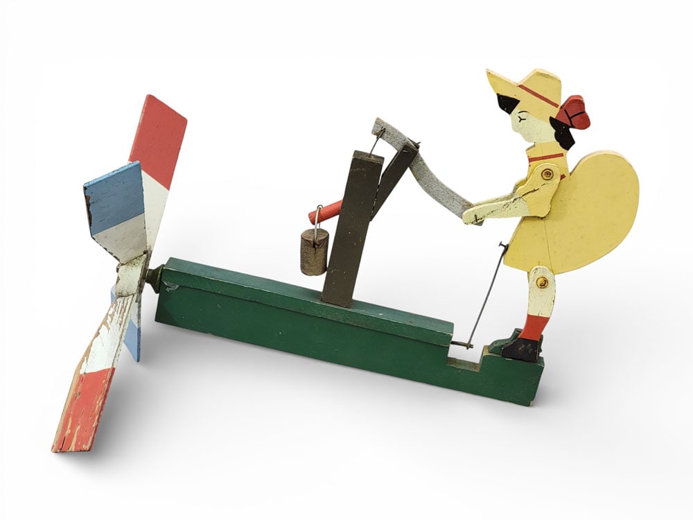 WHIRLIGIG WITH A GIRL AT A WELL: American, mid-20th century, wood. Original paint. 15.5" long. Provenance: a West Virginia collection. NOTE: We are happy to answer questions and take additional photos of lots prior to the auction (th
