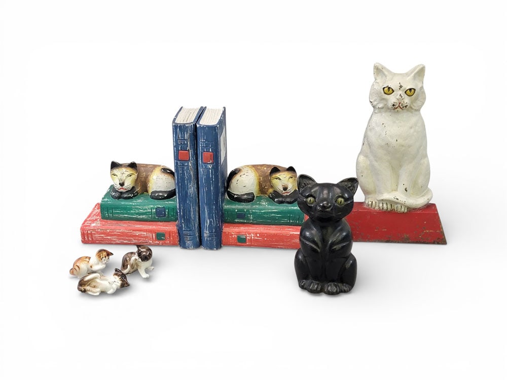 COLLECTION OF CAT DECOR: Early- to mid-20th century, mixed materials. Miscellaneous cat decor including: an Albany Foundry cast iron doorstop in the form of a seated cat, c. 1920; a pair of painted wooden bookends shaped like