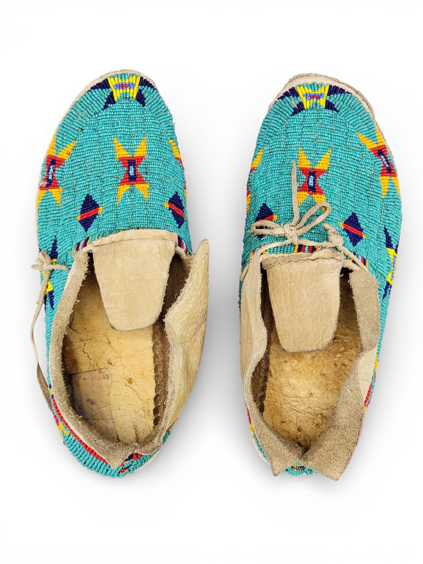 PAIR OF PLAINS BEADED MOCCASINS: 1st half-20th century. With red, dark blue, and yellow designs on a turquoise ground. 10.5" long. Provenance: an Ohio collection. NOTE: We are happy to answer questions and take additional photos of l