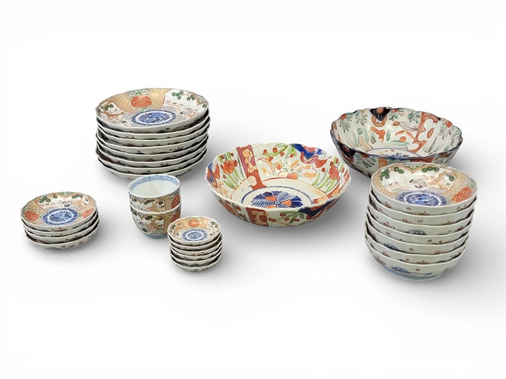 SET OF JAPANESE IMARI TABLEWARE: Japanese, 19th-20th century, porcelain. A set of Imari tableware: 8 plates, 7 rice bowls, 6 small saucers, 4 regular saucers, 2 teacups, and 2 serving bowls in a different pattern. Blue seals on botto