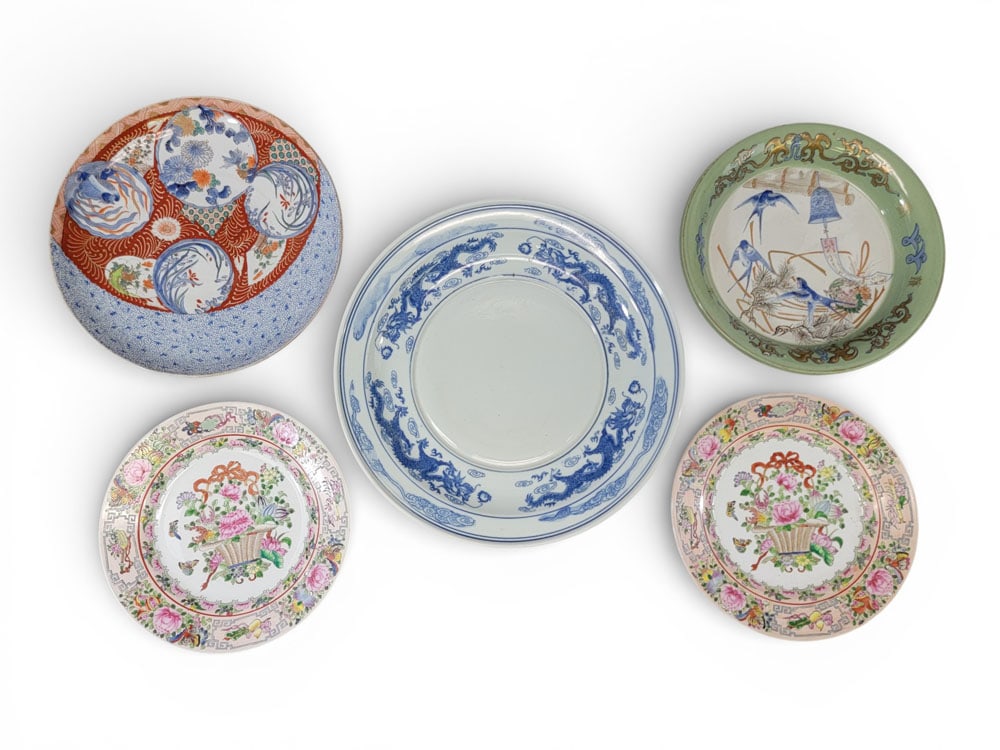 FIVE ASIAN PORCELAIN PLATES: China and Japan, 19th-20th century. Five Asian porcelain plates: two matching Chinese Famille Rose dinner plates; a deep Chinese serving dish with scenes of swallows in flight and a celadon border, si