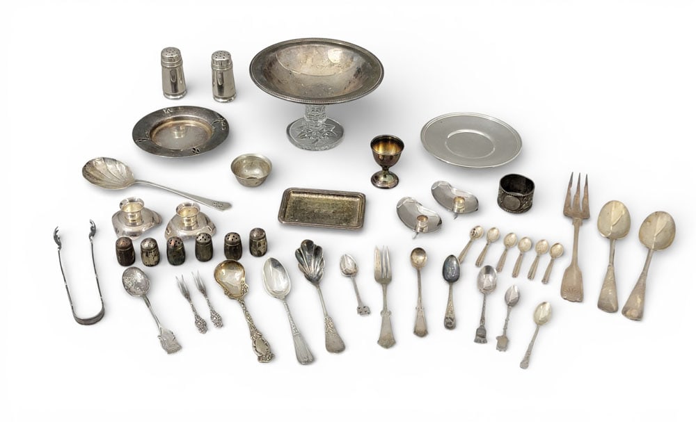 COLLECTION OF SILVER, MOSTLY PLATE AND COIN: Collection of silver flatware and hollowware, mostly coin and plate. Possibly sterling: two serving spoons with worn marks. Plate, coin, and unmarked: six shakers, an egg cup, ice tongs, a souvenir sp