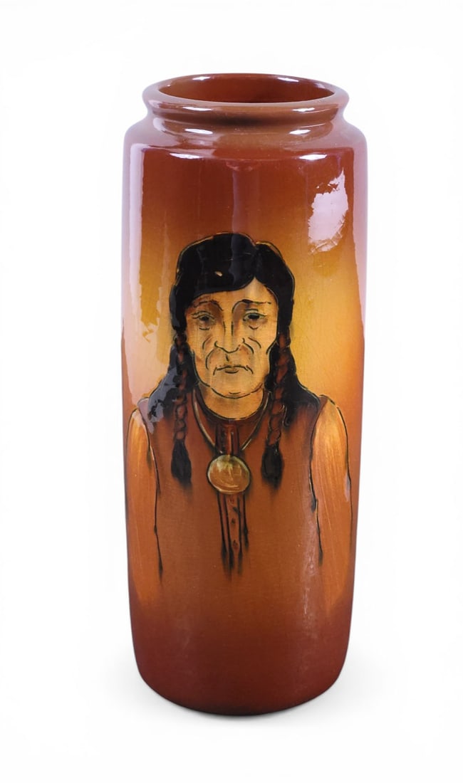 WELLER NATIVE AMERICAN PORTRAIT VASE: Zanesville, Ohio, 1897-1905. A cylindrical vase with a portrait of a Native American, monogrammed, second Dickens Ware line. 10.75" high. Provenance: Collection of Ray and Eva Thomas, Zanesville,