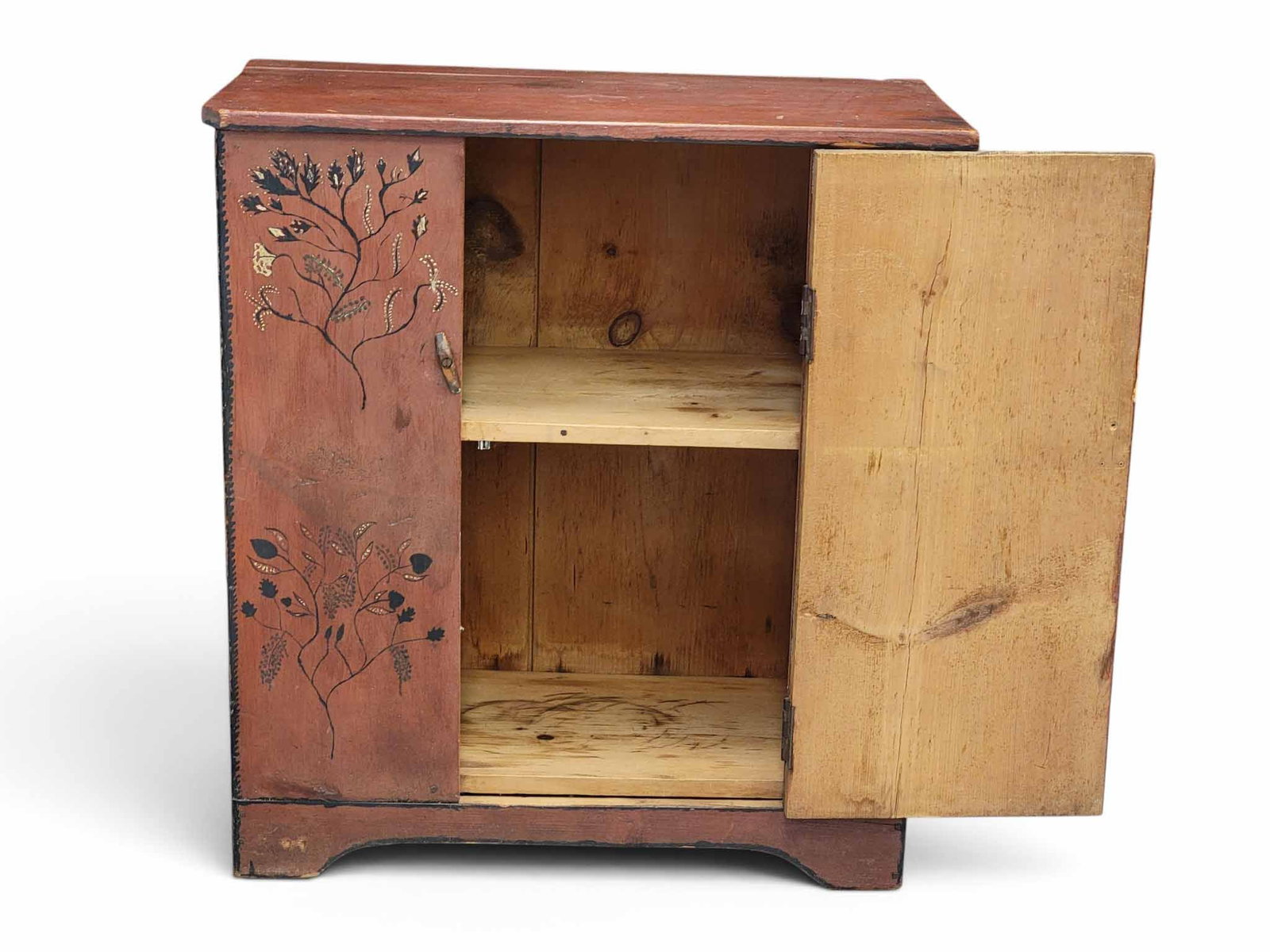 DIMINUTIVE DECORATED CUPBOARD: Possibly Ohio, mid-19th century, pine. Small cupboard with a single plank door, and retaining its original red paint with unusual floral and vining decoration. 36" high, 33" wide, 17" deep.