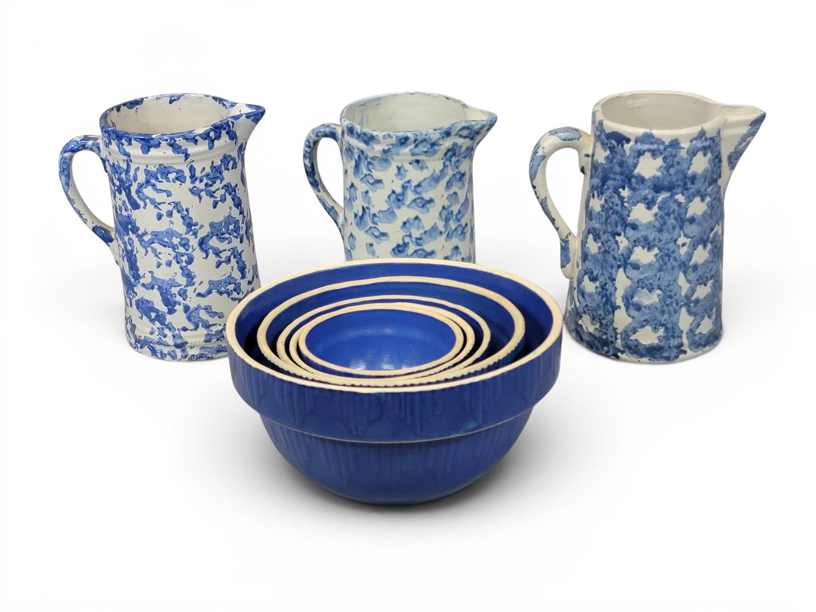 COLLECTION OF "KITCHEN" STONEWARE: Indiana and Ohio, early 20th century. Includes three Ohio blue spongeware pitchers, 9" high each; together with a nested set of 5 "new old stock" bowls by Clay City Pottery, Clay City, Indiana, with