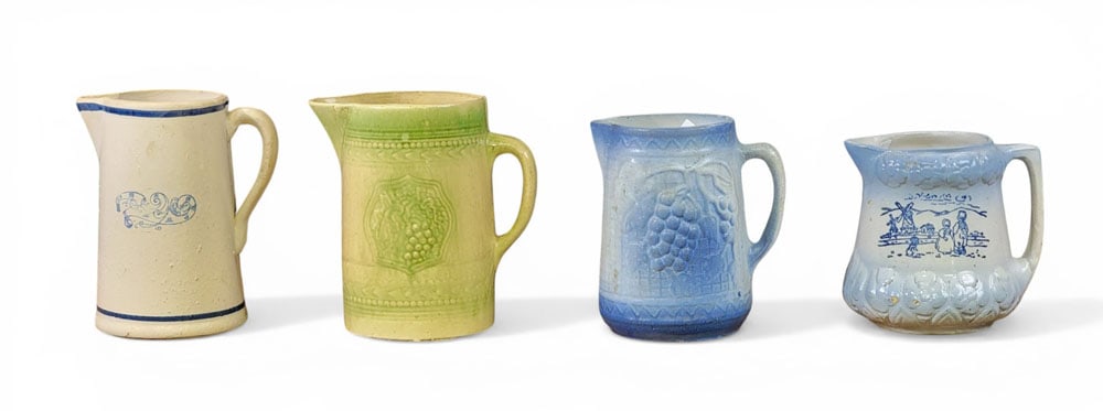 FOUR STONEWARE PITCHERS: American, early 20th century. Three molded pitchers, one with Dutch windmill scene, and various glazes. Tallest is 9" high. Provenance: an Ohio collection. NOTE: We are happy to answer questions and t