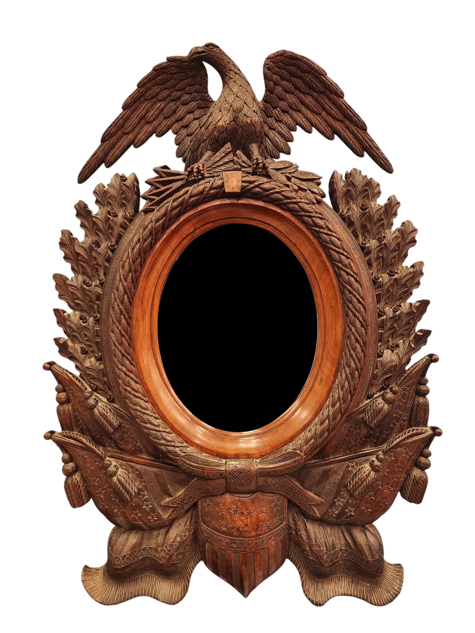 IMPRESSIVE PATRIOTIC CARVED MIRROR: American, early 20th century, mahogany. Oval mirror with carved rope surround, flanked by oak leaves and tiny acorns, surmounted by a spread-winged eagle with arrows and olive branches in its claws, a