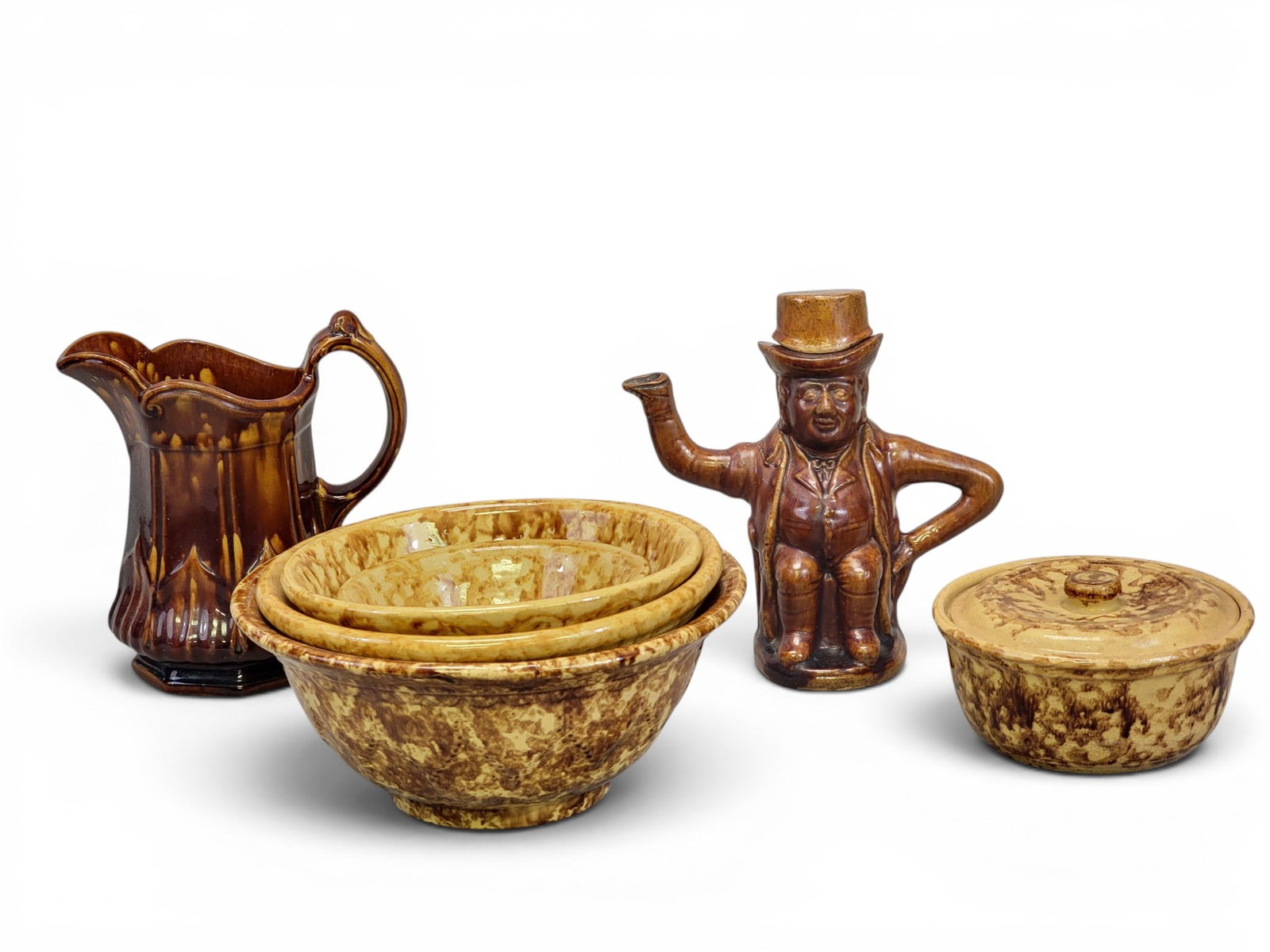 COLLECTION OF ROCKINGHAM WARES: American, mid-19th century. Includes a figural teapot (man in a hat), 8.25" high; a pitcher, 8.25" high; four bowls, 6.25" to 10.5" diameter; and a covered bowl, 6.75" diameter. Provenance: a