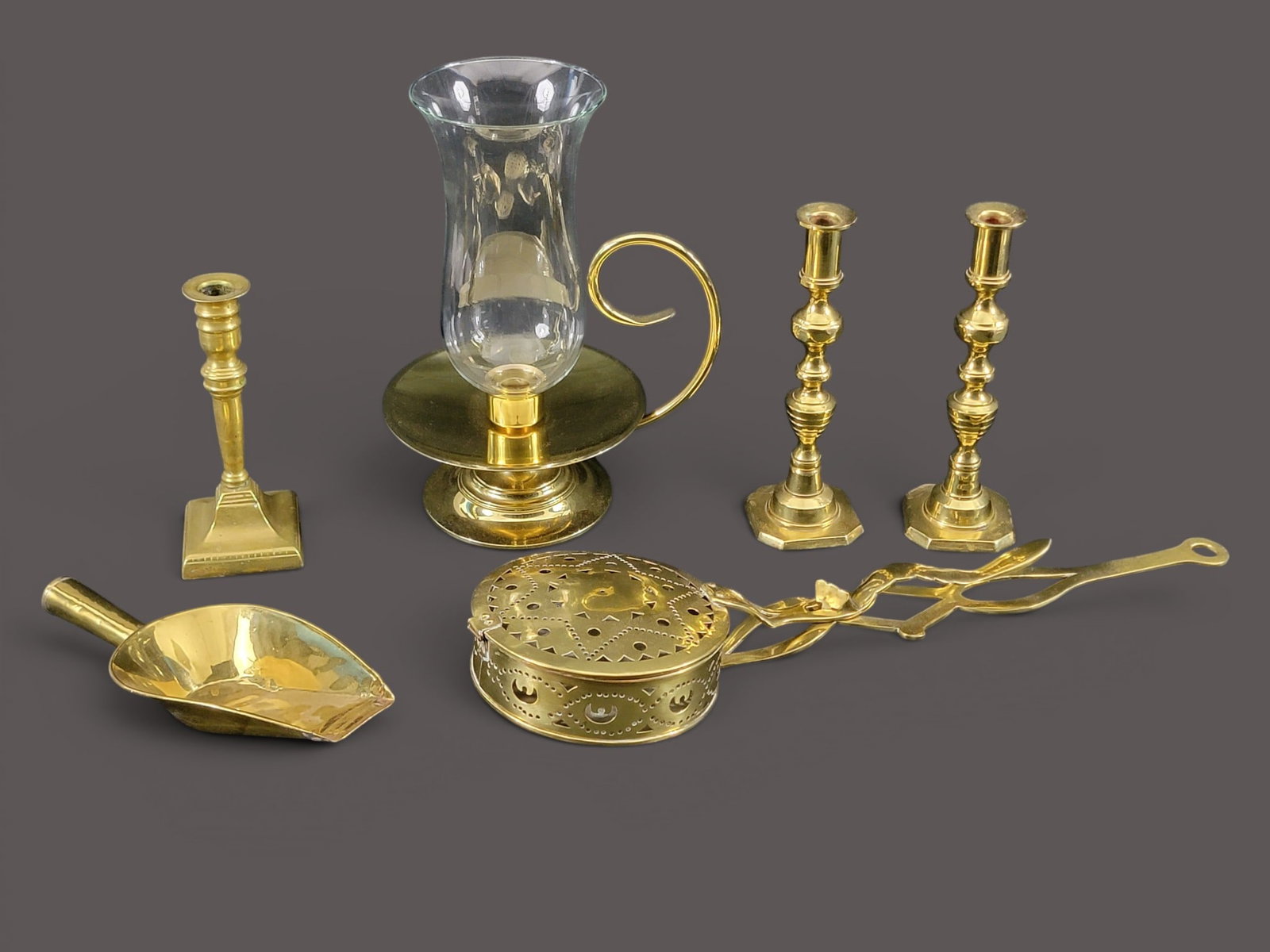 COLLECTION OF BRASS ITEMS: 19th-20th century. Includes a pair and single candlesticks, 8.75" and 10" high; together with a scoop, 11" long; a chestnut roaster, 23" long; and a Baldwin reproduction candleholder with chimney,