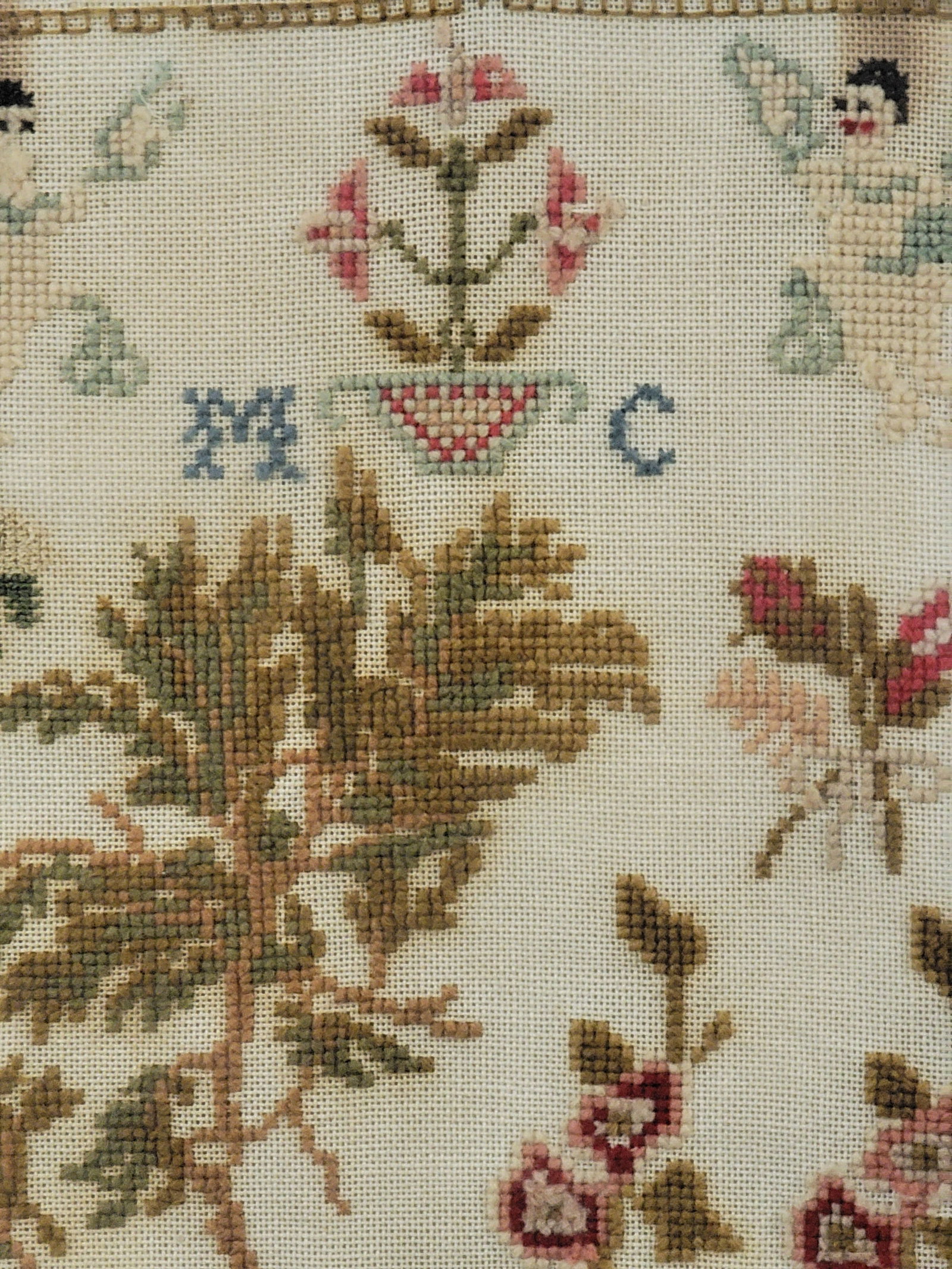 SCHOOLGIRL SAMPLER: American, 19th century, wool on linen. "MC" at center with landscape and angels, and with a floral border. In a period frame, 16" high, 13.75" wide (overall). Provenance: from the collection of Diane