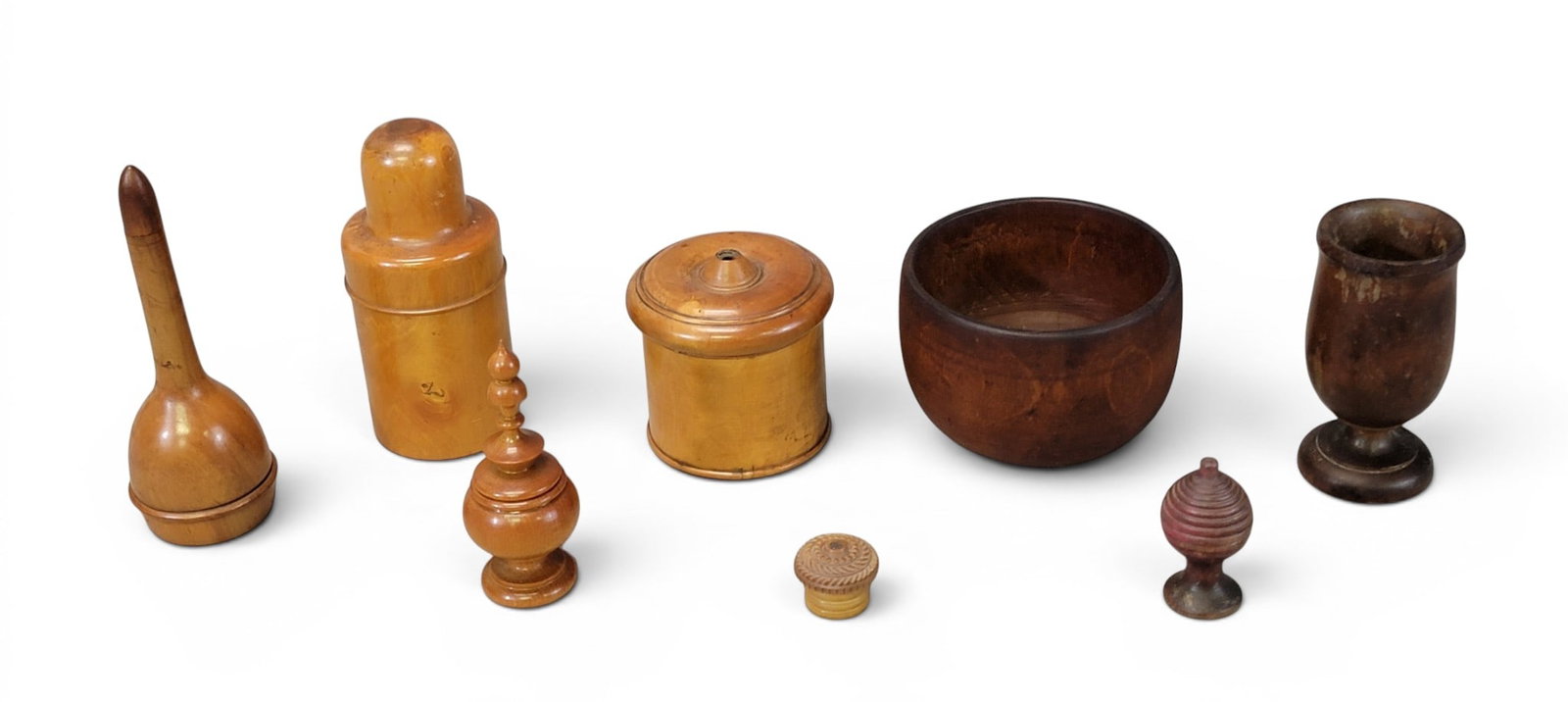 COLLECTION OF TREENWARE: 19th century. Includes a wide cup, a narrow chalice, a bottle holder, a string holder, and three small containers (one of which is vegetable ivory); together with a Harley's Complete Darner, with