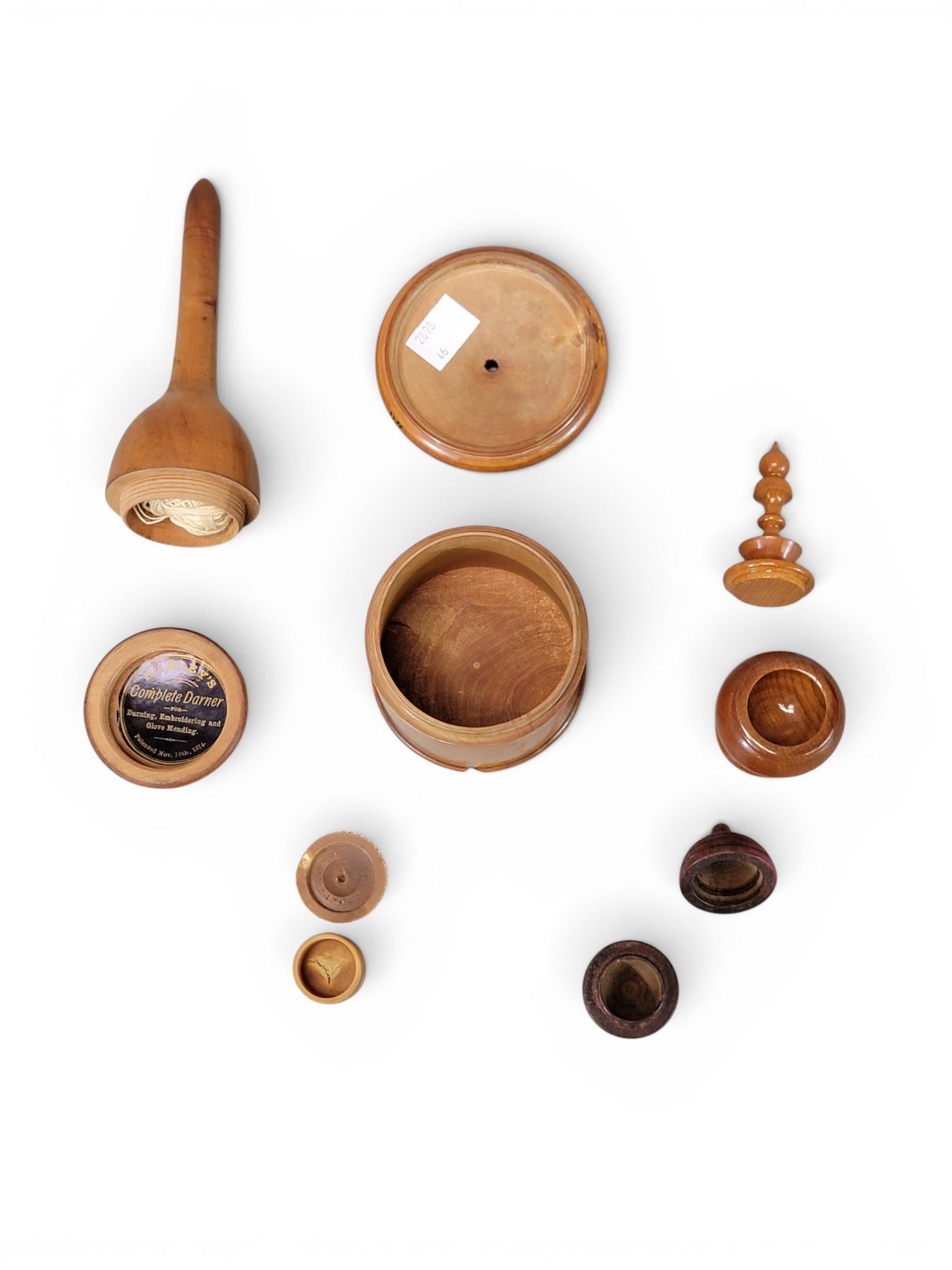 COLLECTION OF TREENWARE: 19th century. Includes a wide cup, a narrow chalice, a bottle holder, a string holder, and three small containers (one of which is vegetable ivory); together with a Harley's Complete Darner, with