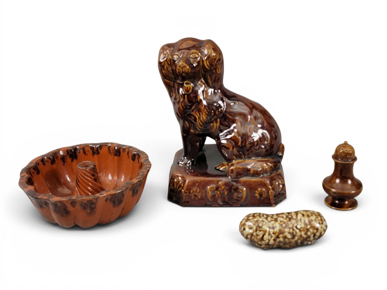 COLLECTION OF POTTERY: 19th century. Includes an East Liverpool, Ohio-style Rockingham dog, 10.5" high; together with a redware mold with manganese splotches, 8.25" diameter; a Rcokingham pepper caster, 4.25" high; and a