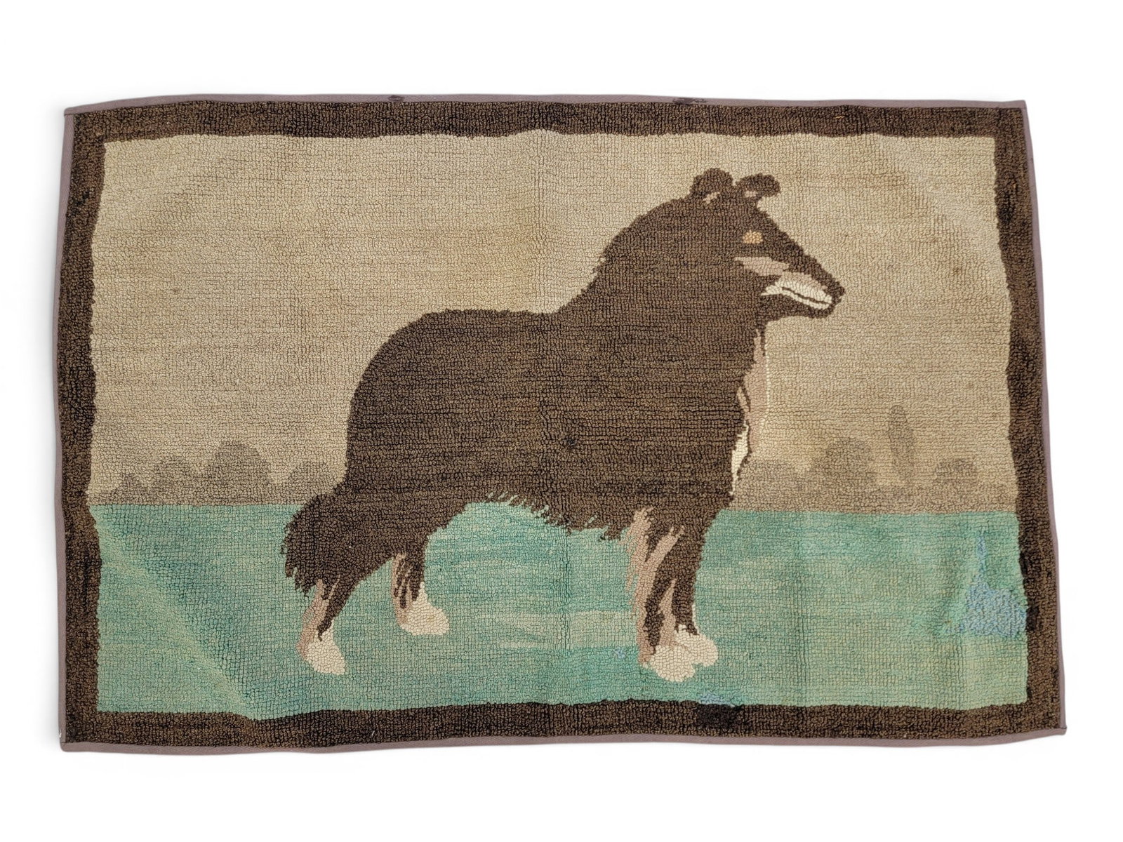 GRENFELL-STYLE HOOKED RUG: 20th century. In the style and color palette of Grenfell Mission hooked rugs, depicting a dog against a landscape. 30.25" high, 45.75" wide. Provenance: a northeast Ohio collection. NOTE: We are
