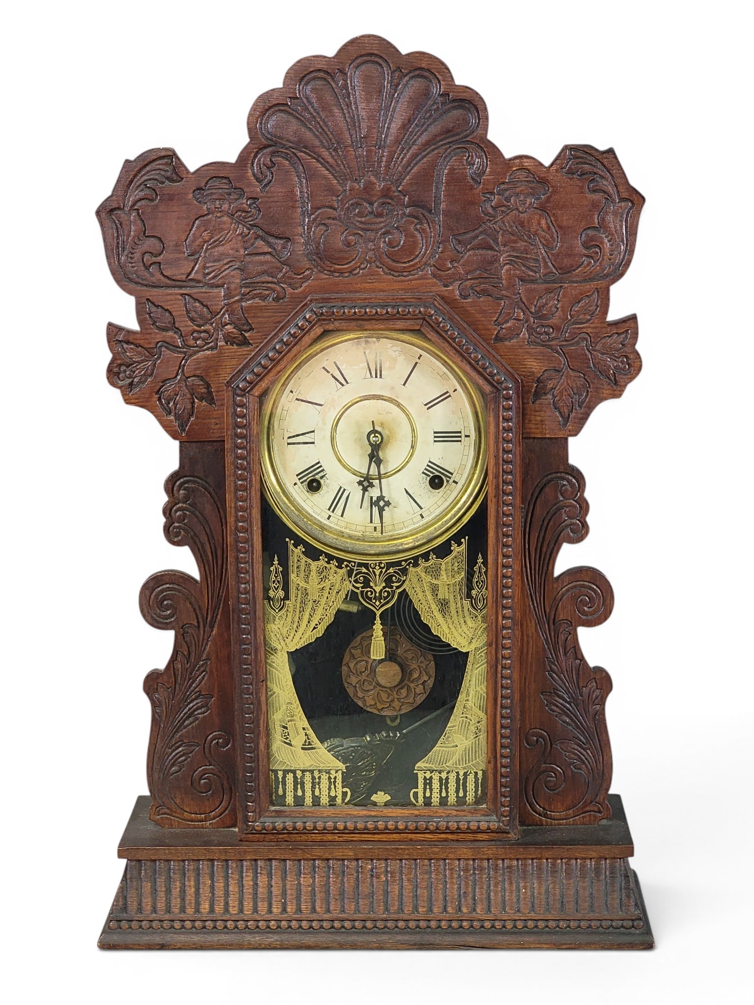 TWO MANTEL CLOCKS: American, late 19th century. Includes an F. Kroeber China No. II Delft clock with fancy brass dial, 11.25" high; together with a Gilbert pressed-oak kitchen clock with drapery door, 24" high. Provenan