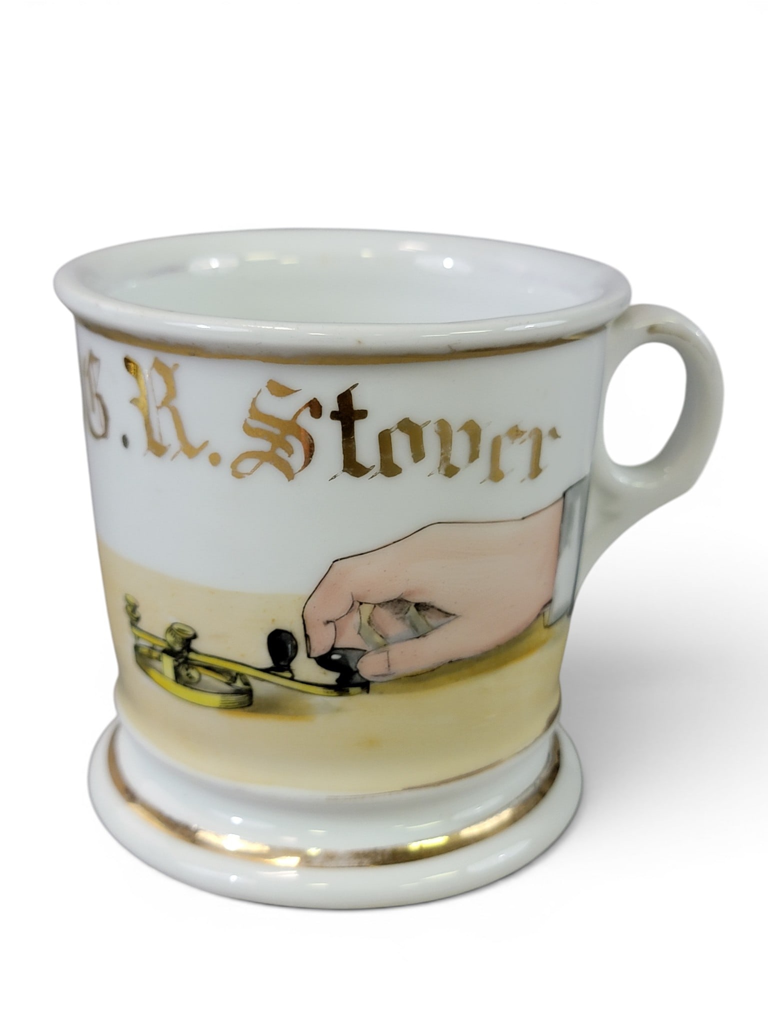 THREE OCCUPATIONAL SHAVING MUGS: Late 19th-early 20th century, porcelain. Includes a telegrapher, a dressmaker or fabric merchant, and a stable operator (marked for Shaw Barber Supply, Wichita, Kansas). 3.5" to 4" high. Provenance: a