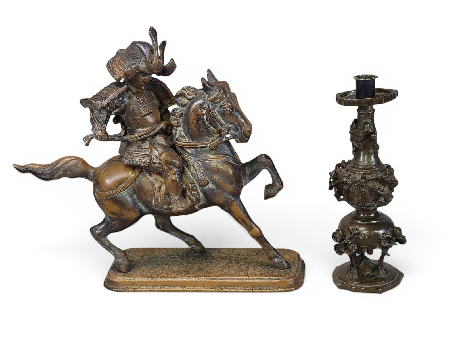 TWO JAPANESE SCULPTURAL WORKS: Includes a Meiji period bronze candlestick with a lobed design, with dragon, birds, ladies, flowers, and turtles, 10" high; together with a bronze-patinated samurai on horseback, 13" long.
