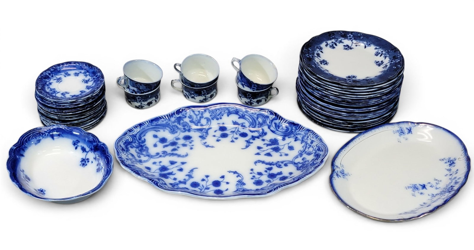ASSEMBLED SET OF FLOW BLUE CHINA: Various makers including Grindley and Wood, 19th-20th century, mostly similar patterns. Plates, platter, serving pieces, and cups/saucers. Provenance: Collection of Bob and Maxine Edwards, New Philade