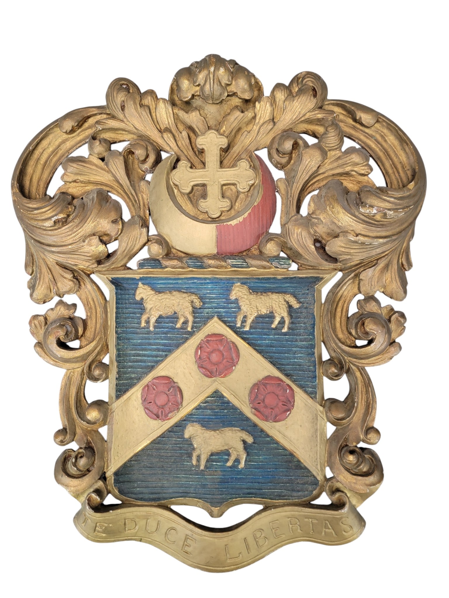 CARVED AND PAINTED FAMILY CREST: English, late 19th century, oak. Probably for the Crosby family, with a cross surmounting a shield with sheep and Tudor roses, over the motto "TE DUCE LIBERTAS" (With Liberty as Our Guide). 24" high,