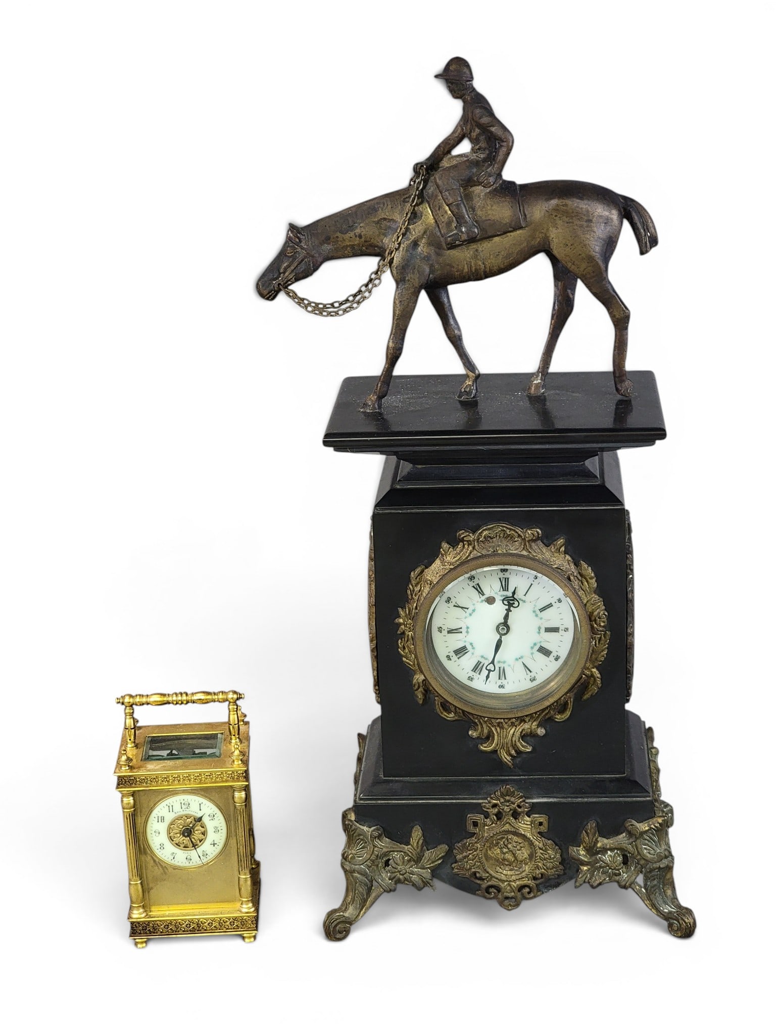 TWO CLOCKS: Early 20th century. Includes a slate and patinated clock with a horse and jockey finial and enameled porcelain side panels, 20" high; together with a Bell Brothers, Paris, gilt brass carriage clock,