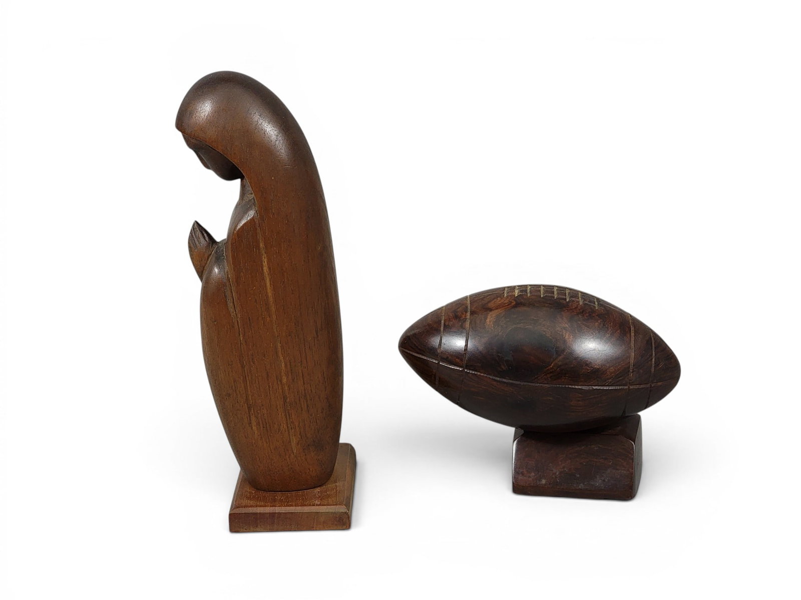 TWO FOLK ART CARVINGS: 20th century. Includes a walnut praying woman (probably Mary), 11" high; together with an ironwood football on base, 8" long. NOTE: We are happy to answer questions and take additional photos of lots