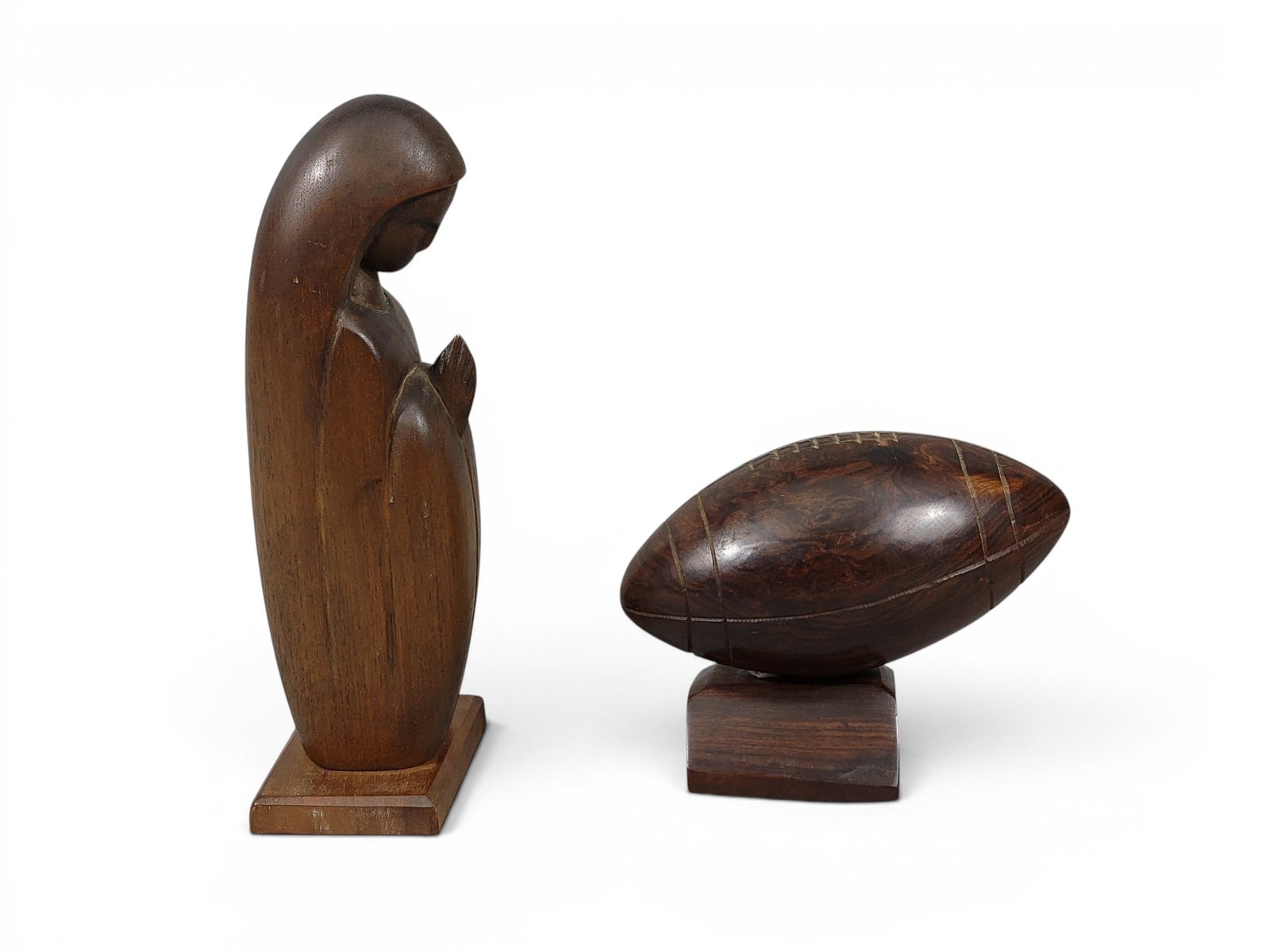 TWO FOLK ART CARVINGS: 20th century. Includes a walnut praying woman (probably Mary), 11" high; together with an ironwood football on base, 8" long. NOTE: We are happy to answer questions and take additional photos of lots