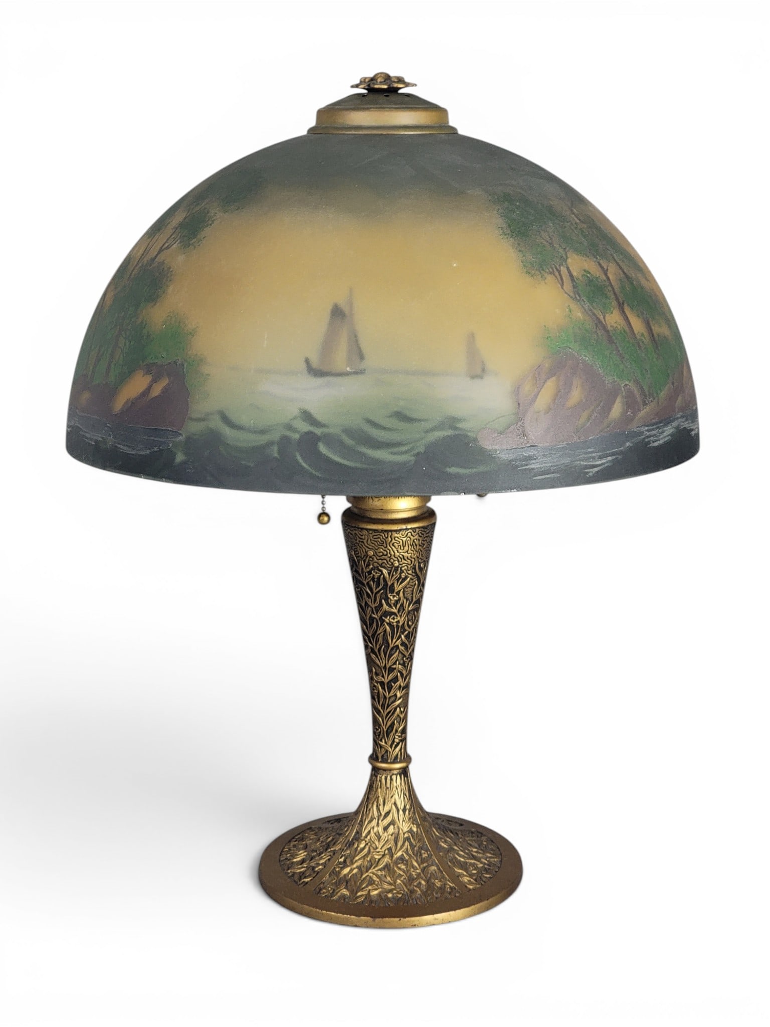 REVERSE-PAINTED TABLE LAMP: Retains remnants of a paper label, possibly Pittsburgh, 1920s. Patinated base with cast "1925" on underside, the reverse-painted shade with sailboats. 22" high; shade is 16" diameter. Provenance: a