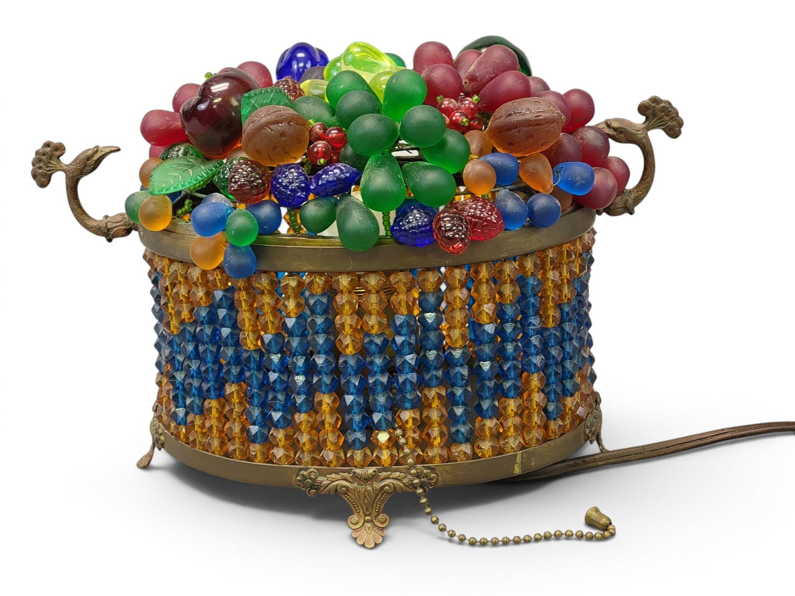 CZECH GLASS FRUIT BASKET LAMP: Marked "MADE IN CZECHOSLAVAKIA", Early 20th century. Patinated frame, the base a beaded basket with bird handles, the top comprising glass fruit and nuts. 7" high, 10.25" long. Provenance: a