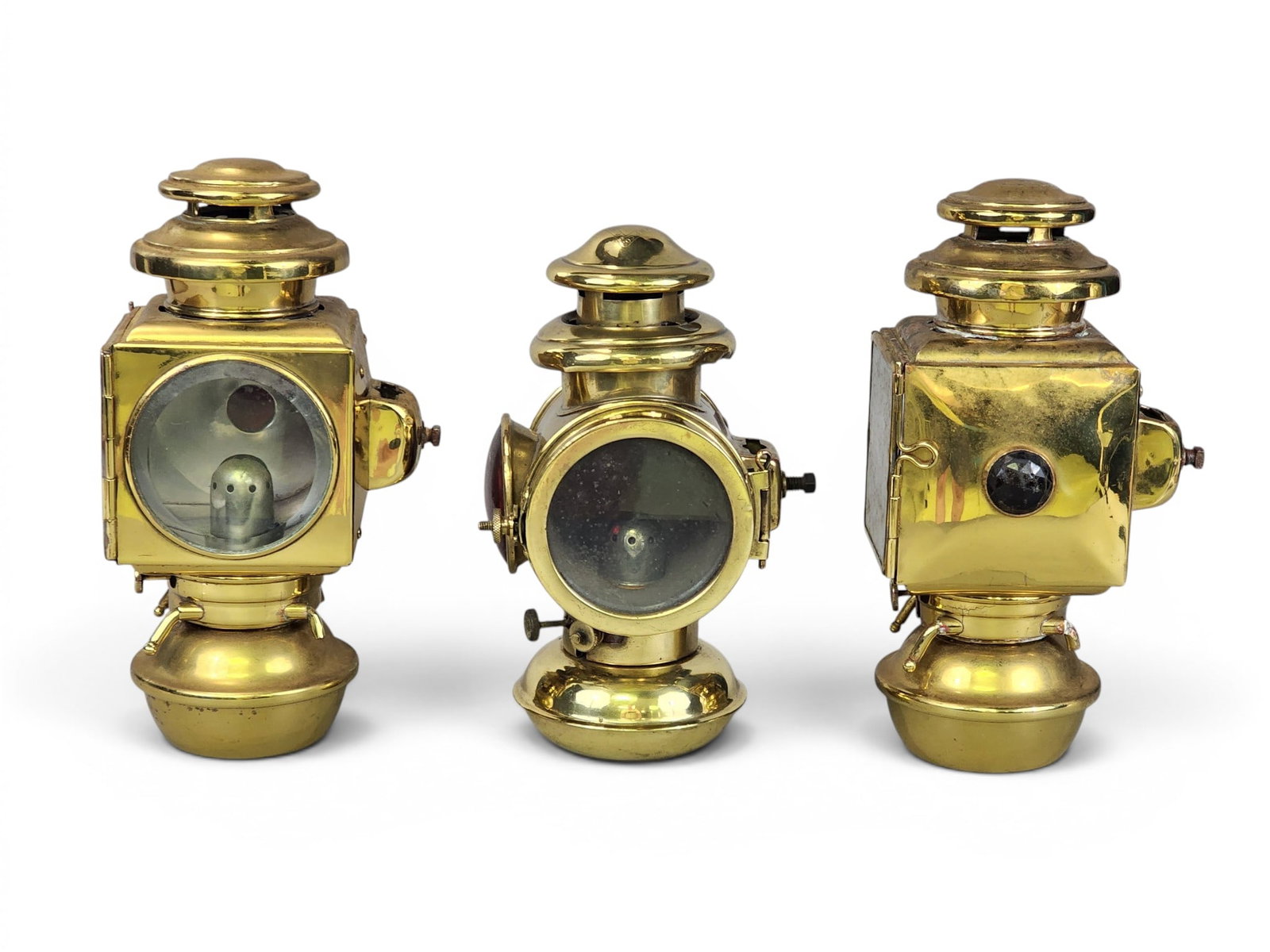 THREE BRASS AUTOMOBILE LAMPS: Includes a left/right pair of E. and J. lamps, Detroit, Michigan, patent date 1908, with faceted red crystal on the back side, 11.25" high; together with a single Corcoran lamp, Cincinnati, Ohio, with