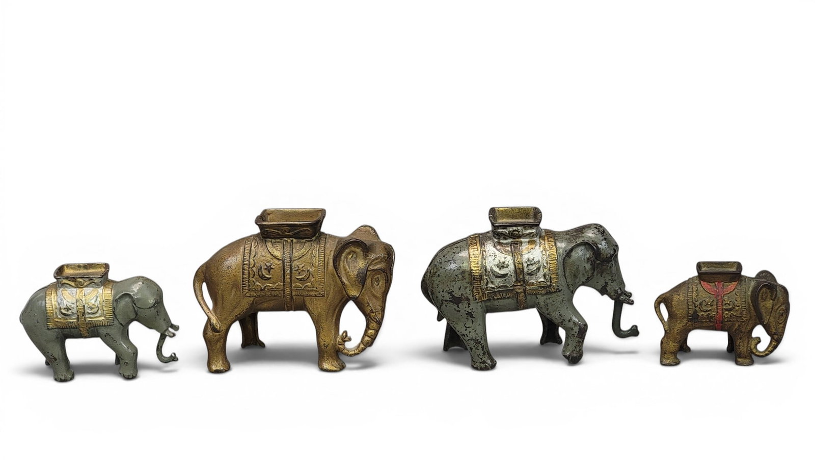 FOUR CAST IRON ELEPHANT BANKS: AC Williams. All Elephants with Howdah: Small (Moore 457), Large (Moore 474), with jointed trunk (Moore 476) and small with jointed trunk (Moore 477). Provenance: a northeast Ohio collection. NOTE: We