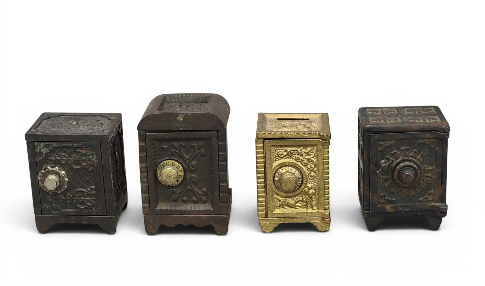 FOUR CAST IRON SAFE BANKS: Includes a safe with round currency slot, 4.75" high; Ideal Security, 4.125" high; Kenton Savings Deposit, 4" high; and a combo safe with boy and dog, 3.875" igh. Provenance: a northeast Ohio collecti